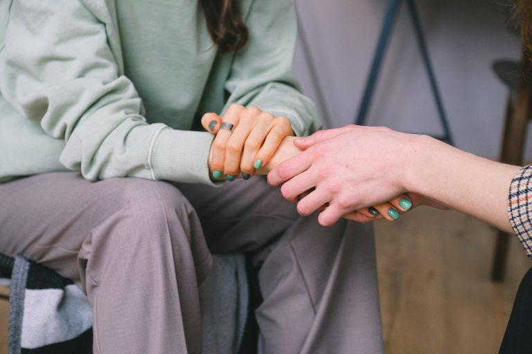 Una persona sostiene la mano de otra, apoyo en la terapia para el trauma